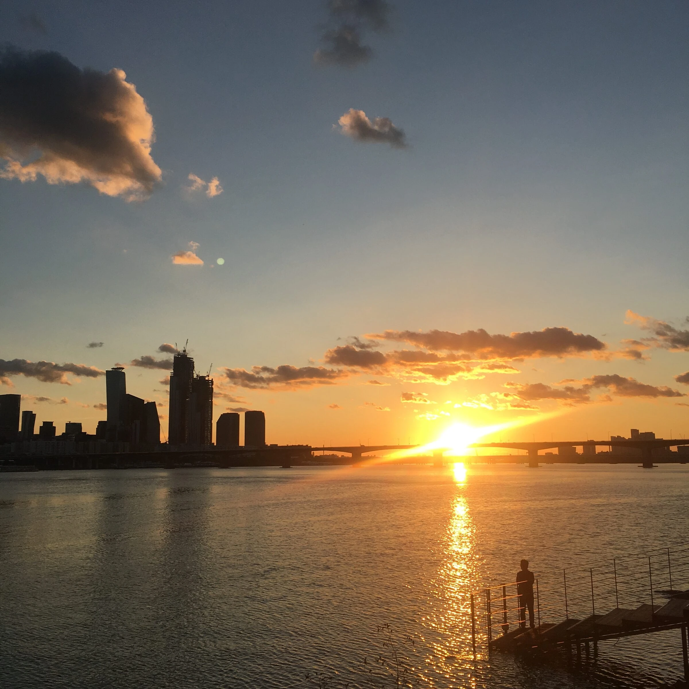 A vivid golden sunset over the Han River at Ichon, the sun setting behind a bridge.