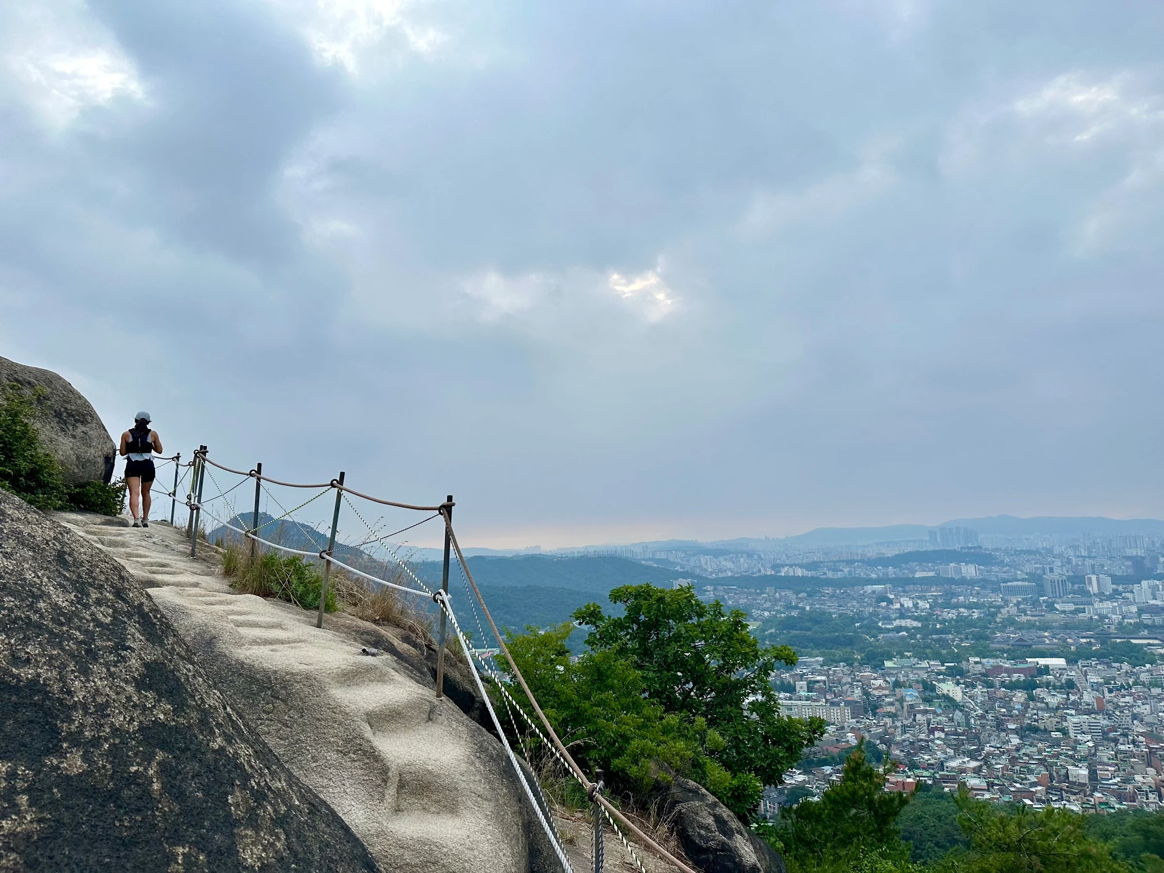 A runner on the granite ridge of the Seoul City Wall at Inwangsan, the city spread out below.